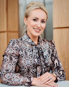 Chief executive seated at a table, smiling in a modern office with wood-panel backdrop